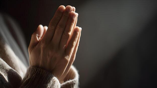 Hands folded in prayer with warm lighting